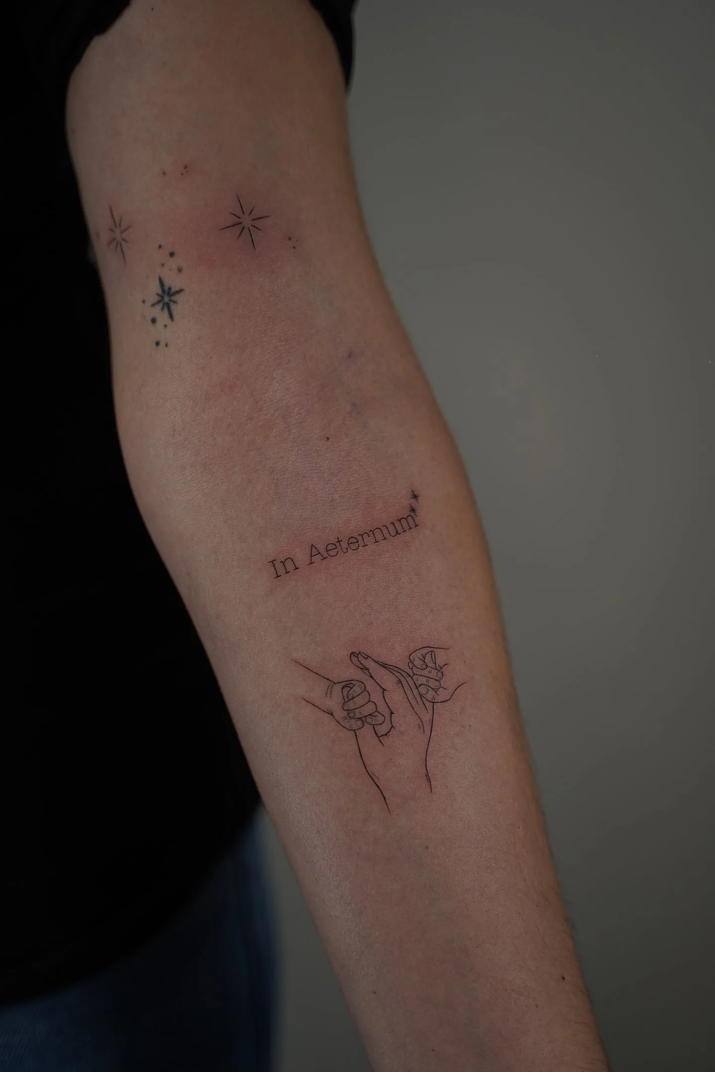 Tatuaje fineline estrellas texto In Aeternum y manos entrelazadas madrid