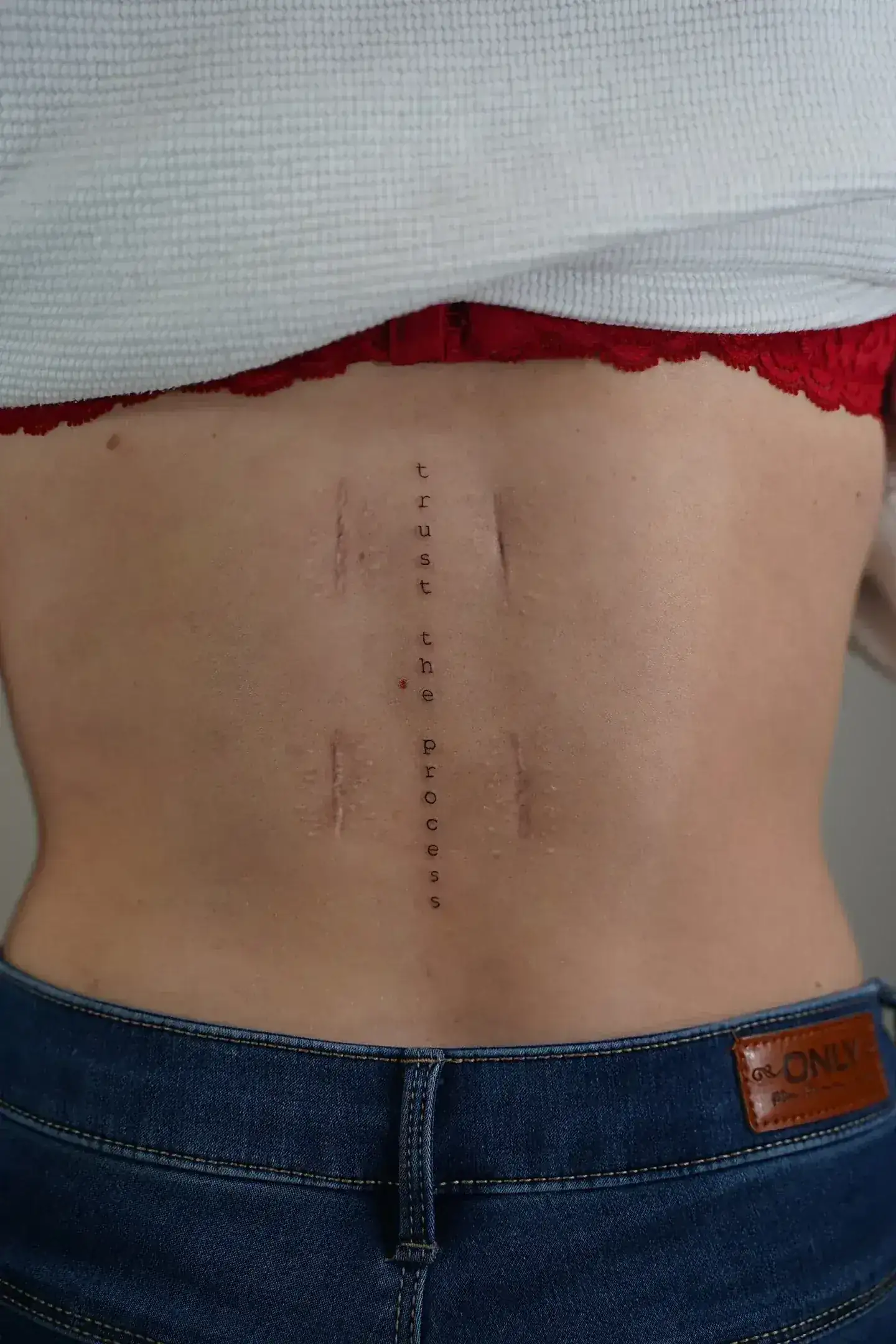 Tatuaje fineline frase trust the process vertical en espalda madrid