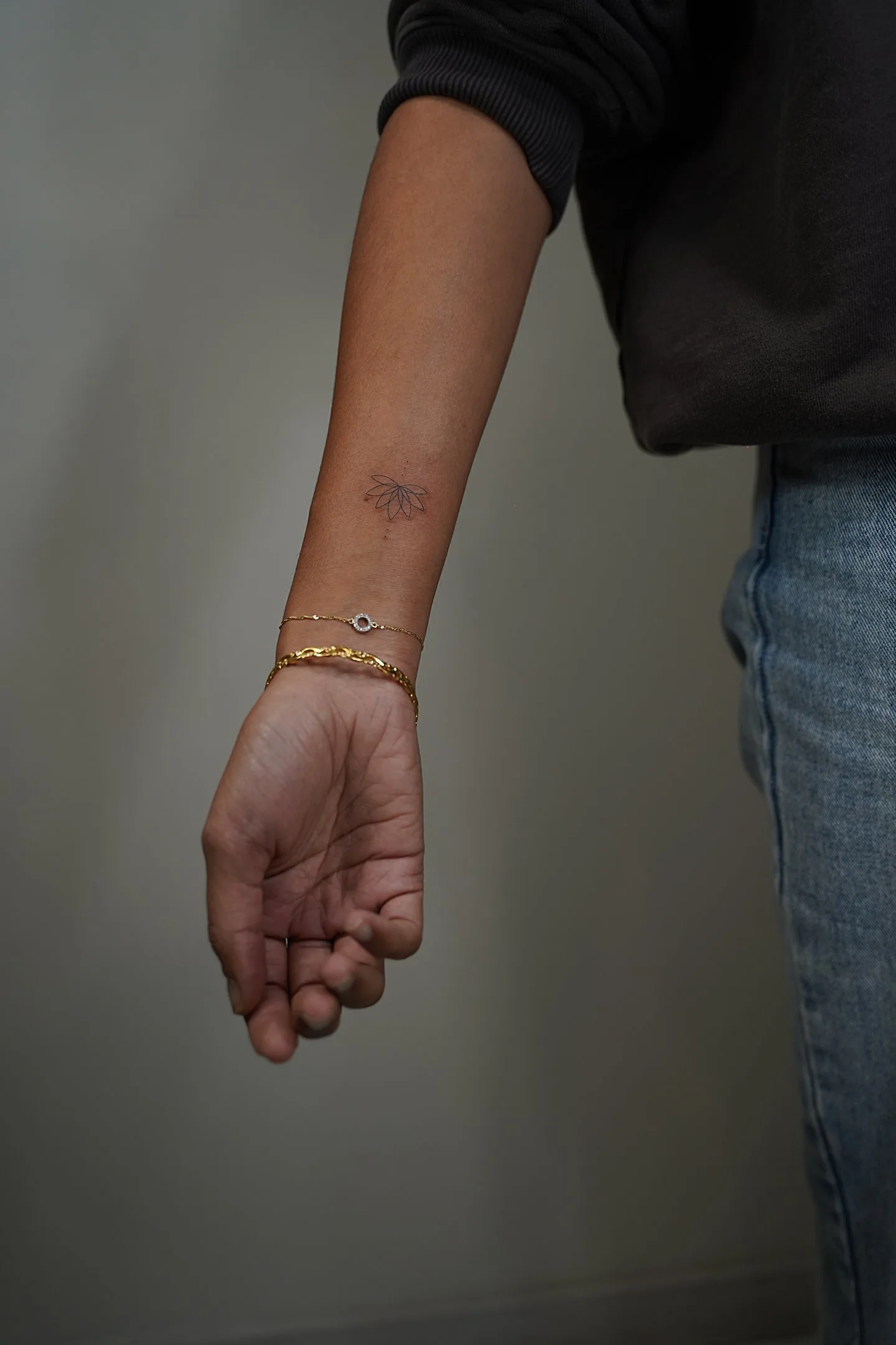 Tatuaje fineline flor de loto minimalista en muñeca madrid