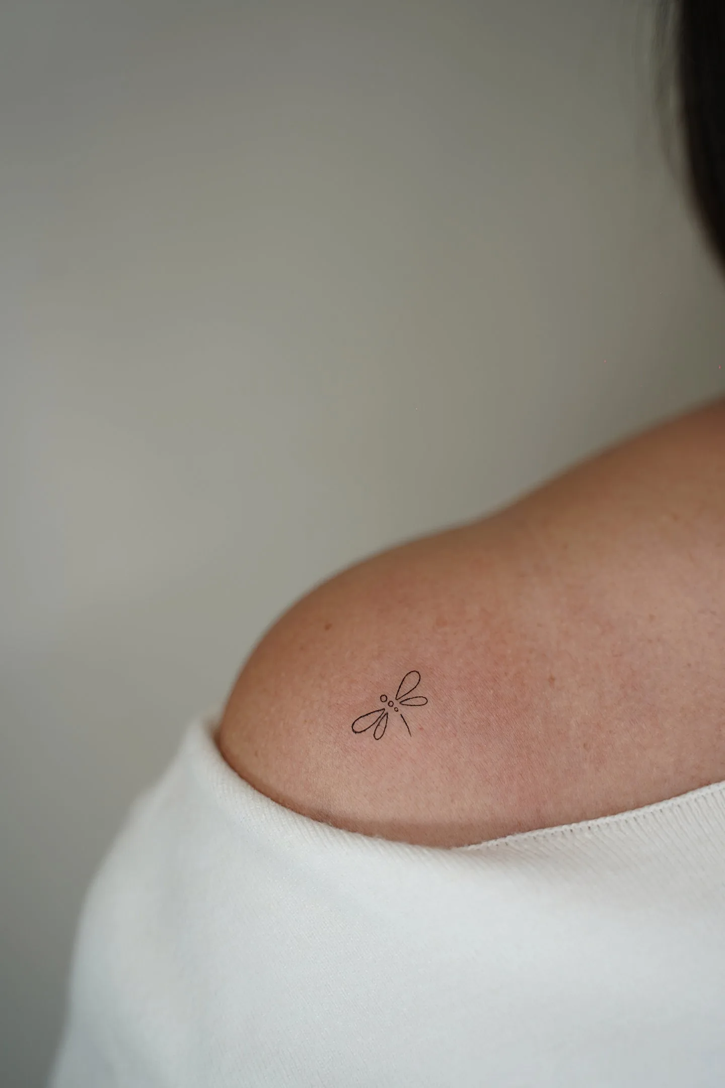 Tatuaje fineline libélula minimalista en una línea en hombro madrid