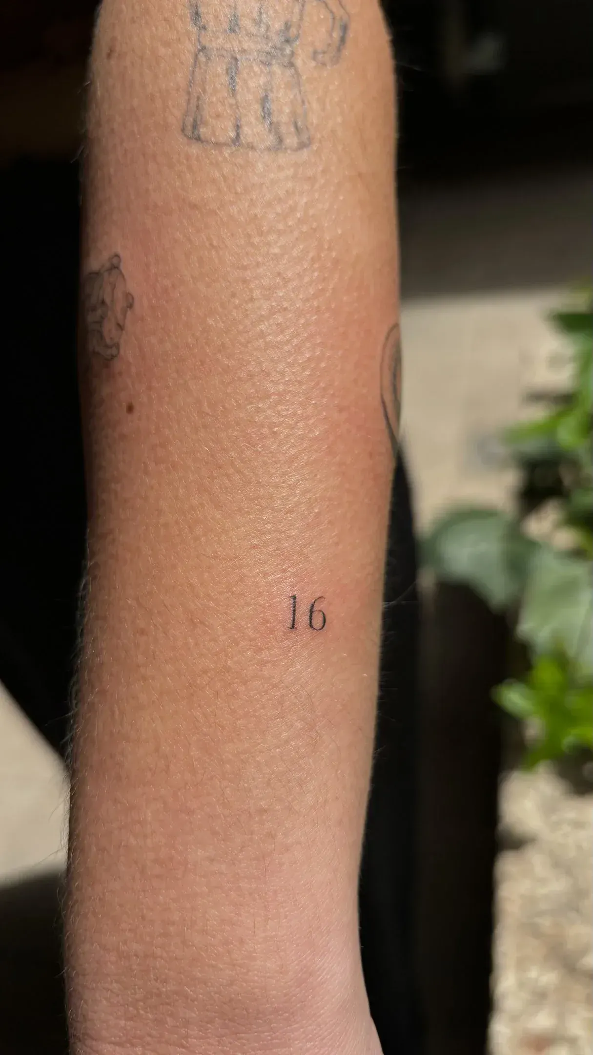 9) "16" en tipografía serif en el antebrazo