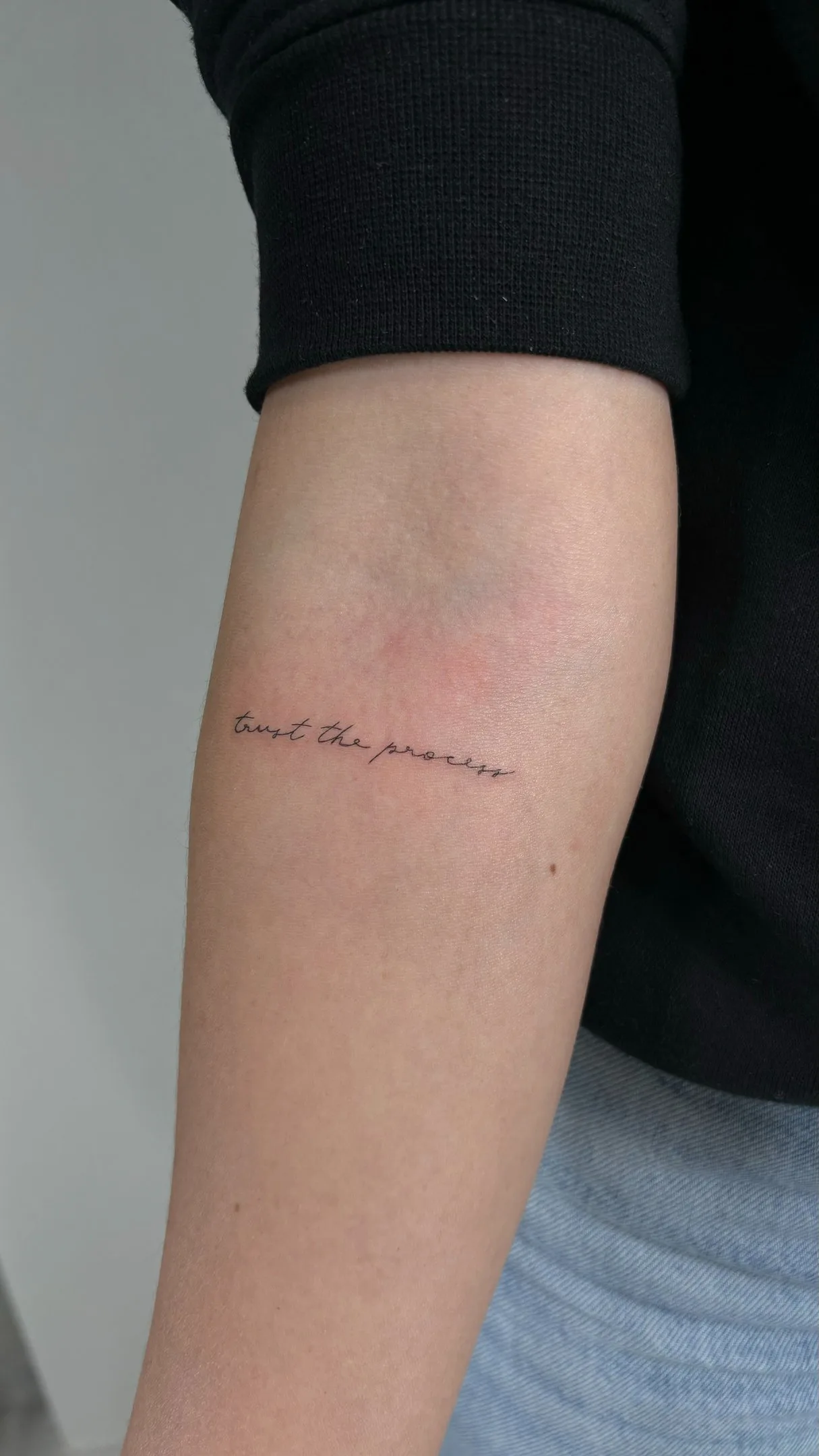 17) "Trust the process" en cursiva en el antebrazo