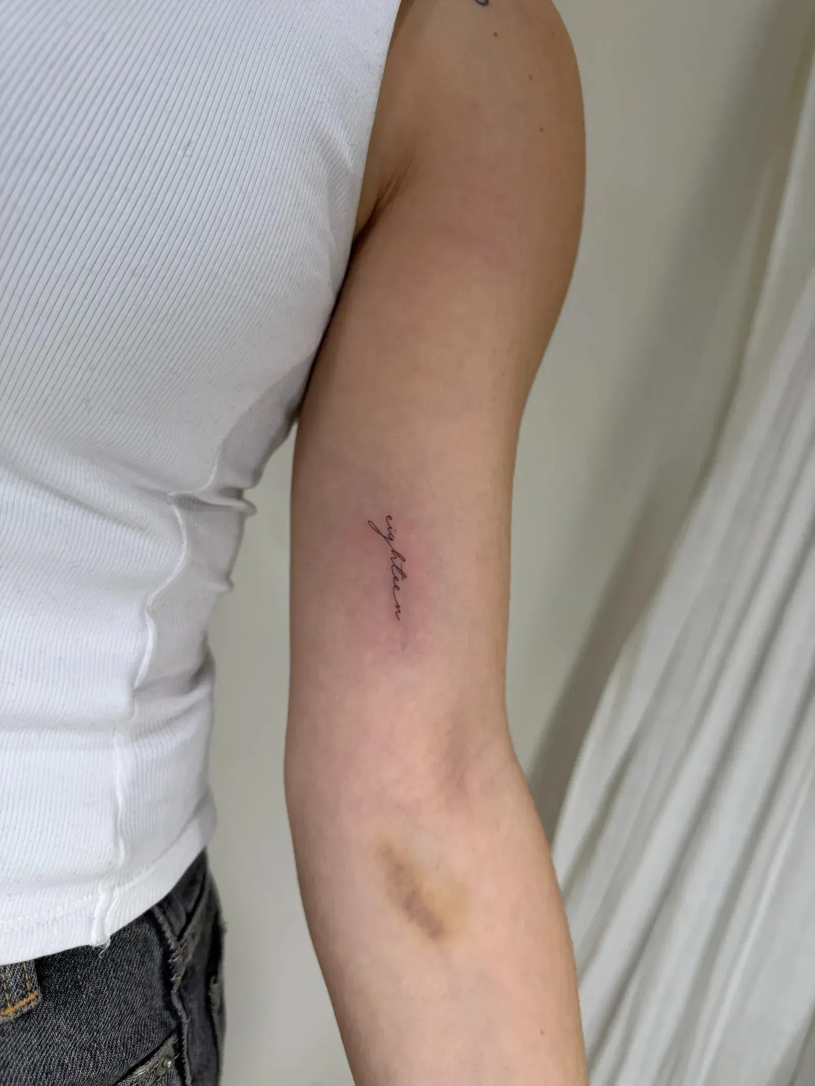 54) "eighteen" en cursiva vertical en el brazo