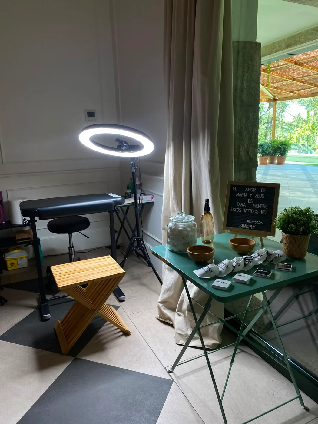 Corner de tatuajes fine line de Sinkply montado en una boda en Madrid, con camilla, aro de luz y pizarra personalizada de los novios