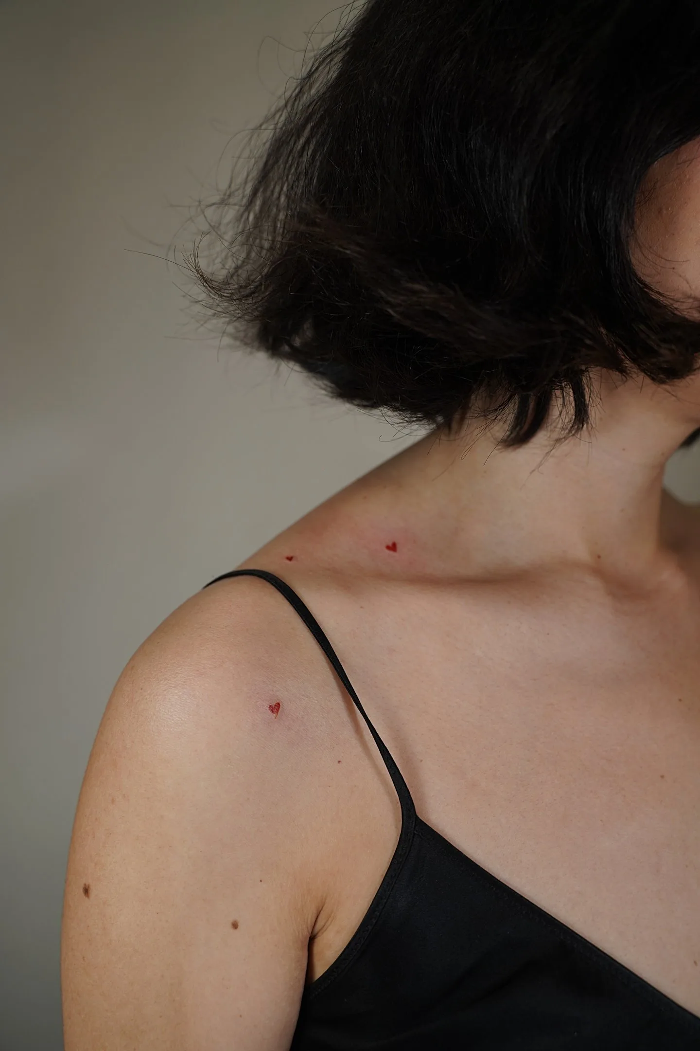 Fine line micro heart freckle tattoo in red ink near collarbone — Sinkply Madrid