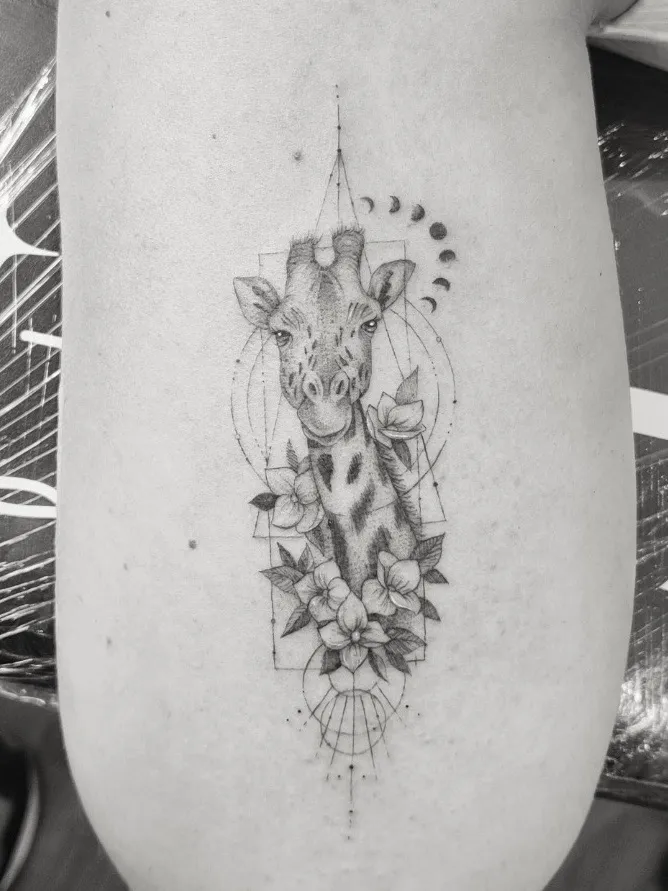Tatuaje microrealismo geométrico jirafa con flores y fases lunares madrid