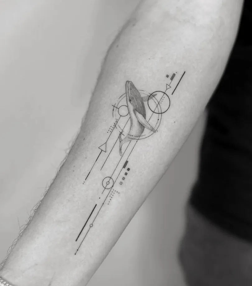 Tatuaje microrealismo geométrico ballena saltando con círculos y flechas en antebrazo madrid