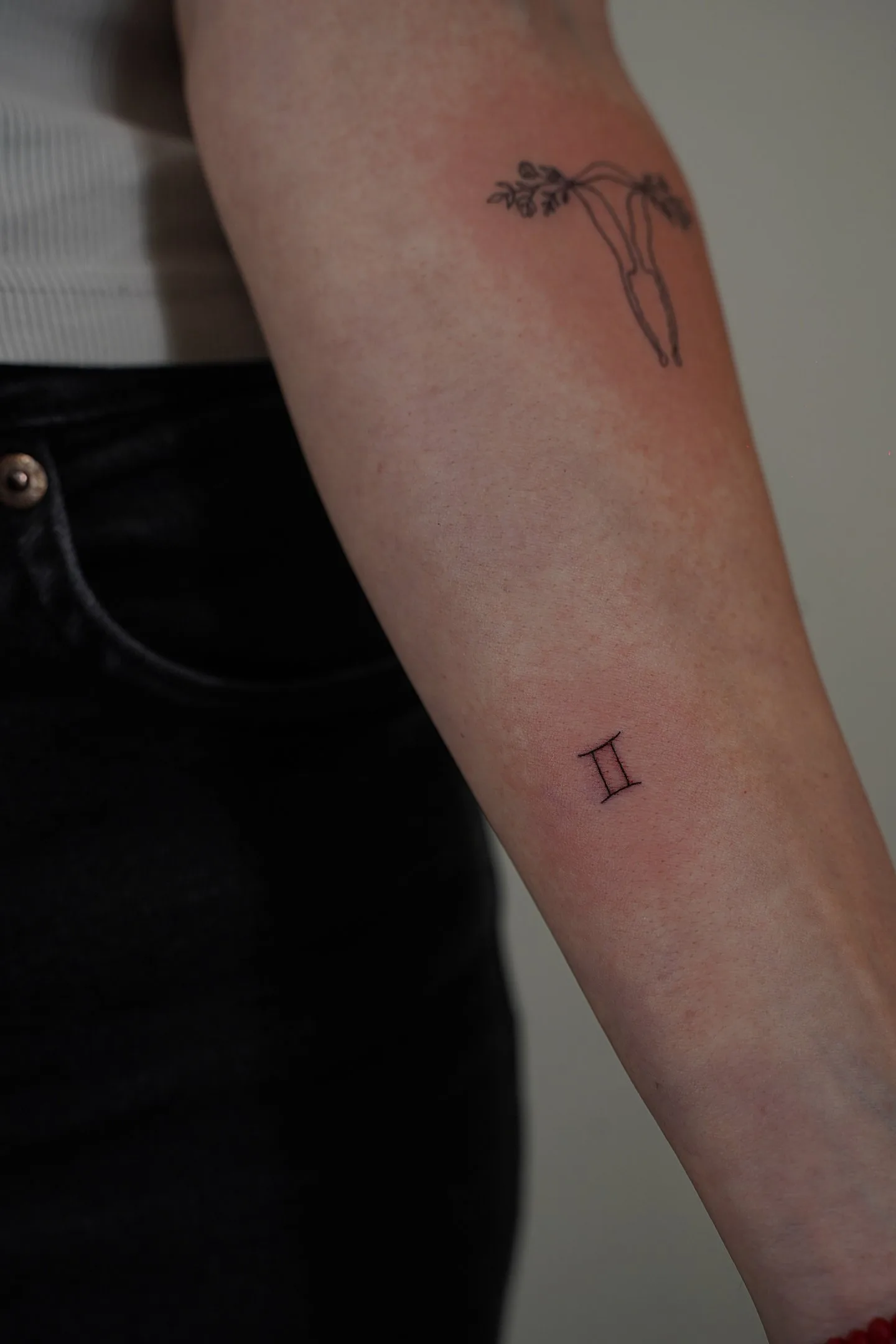 Fine line tattoo Madrid — Gemini zodiac symbol in fine line on the forearm