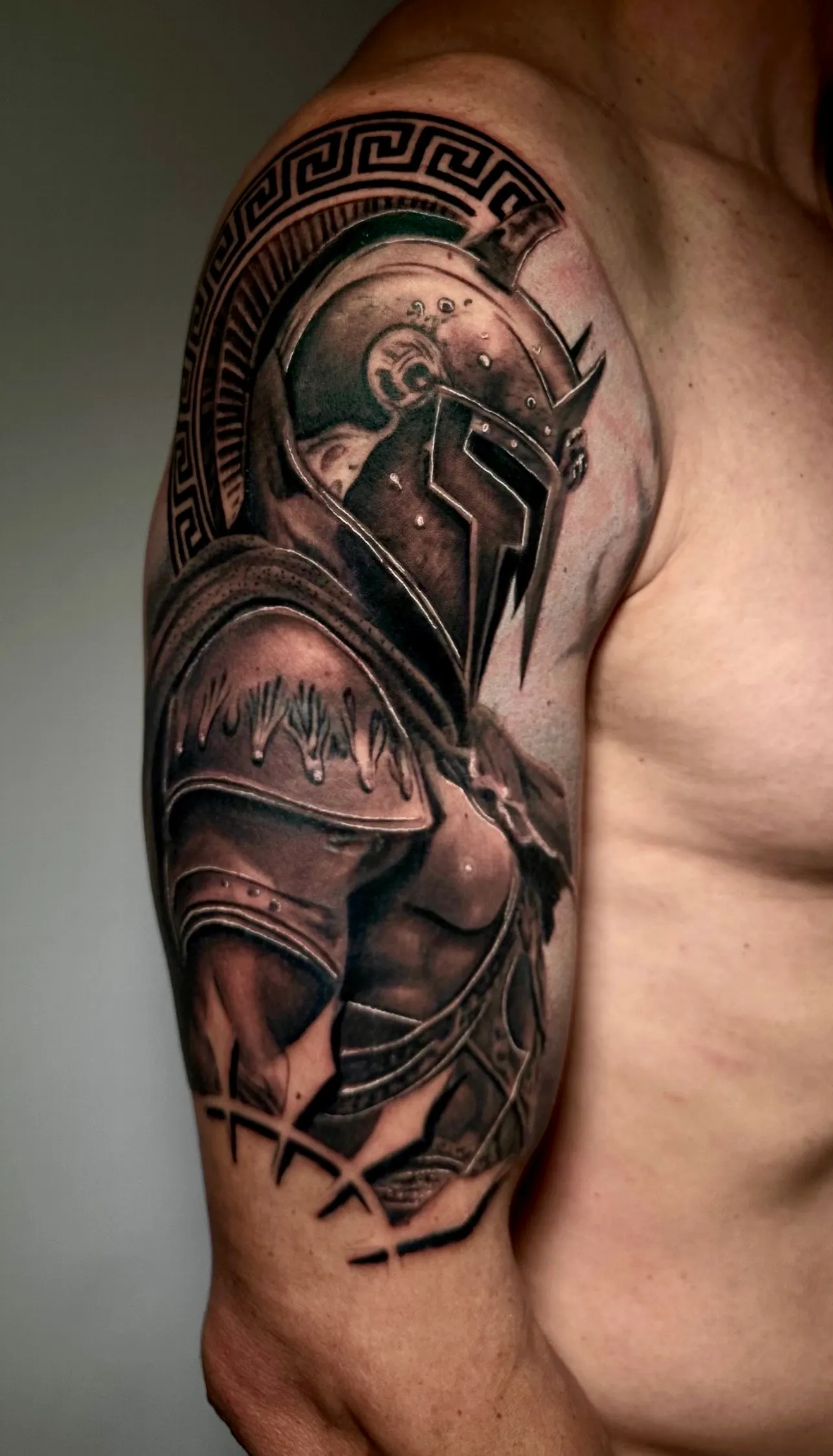 Tatuaje realismo guerrero espartano con armadura completa y greca griega madrid