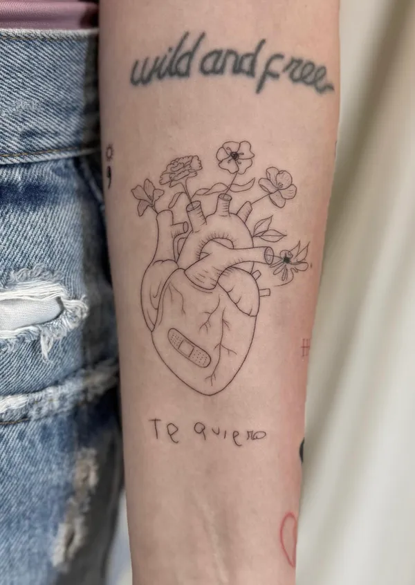 Tatuaje fine line de un corazón anatómico con flores, por Oriana en Sinkply Madrid