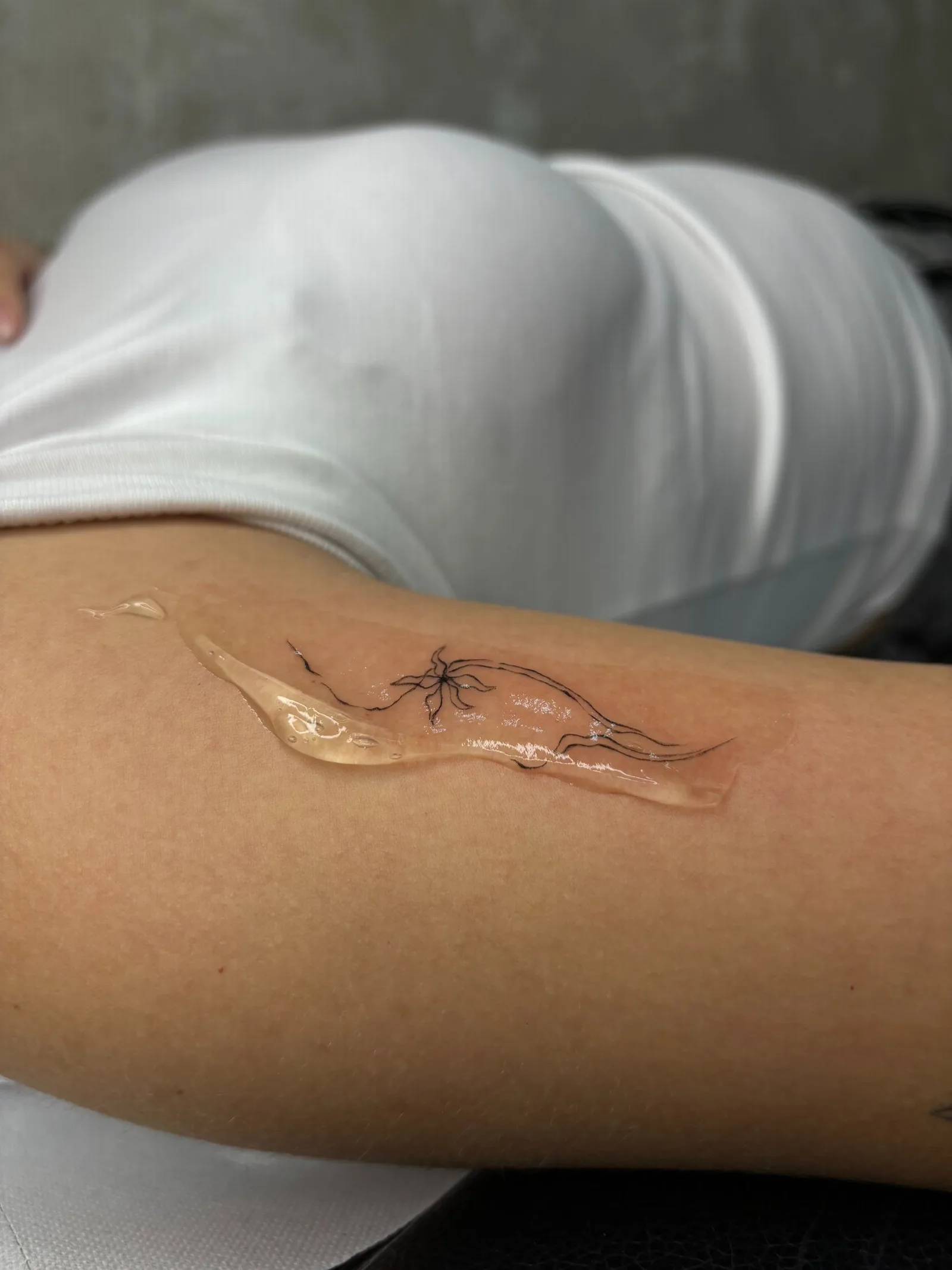 Delicate floral line tattoo inked during a short Madrid trip