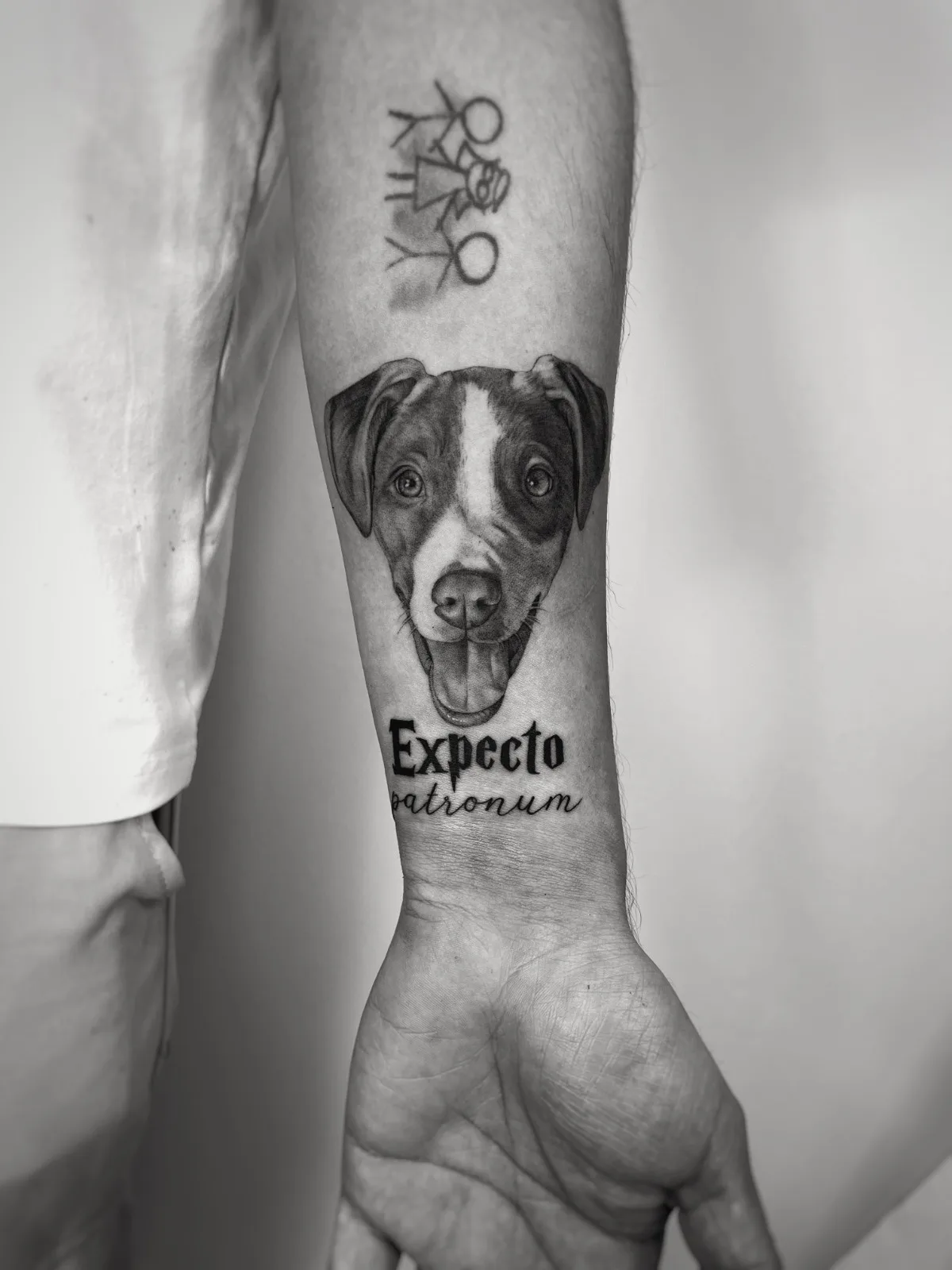 Tatuaje fineline en Madrid de retrato microrealista de perro con lettering Expecto Patronum