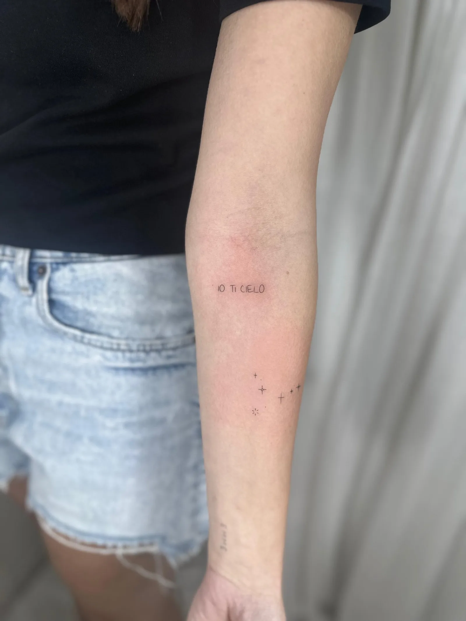 Tatuaje fineline en Madrid con lettering IO TI CIELO y constelación de estrellas pequeñas