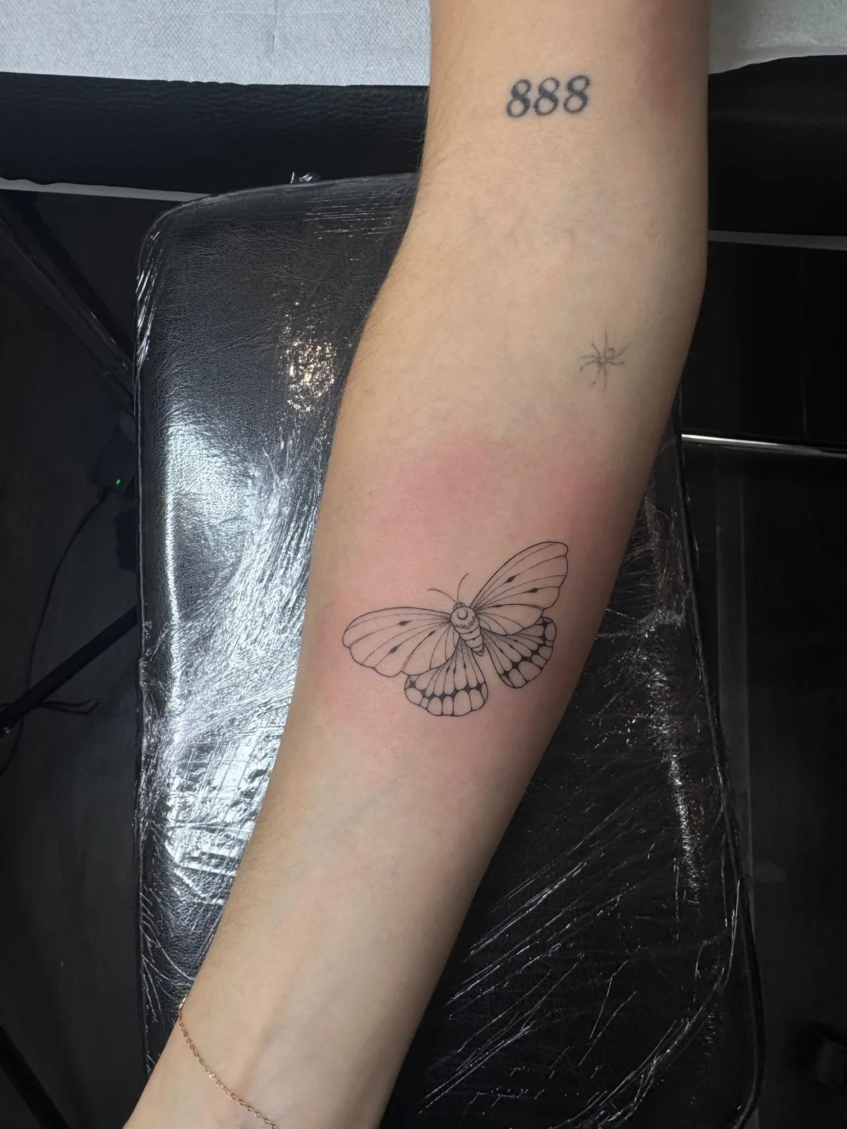 Tatuaje fineline en Madrid de mariposa nocturna con detalle entomológico acompañada del número 888