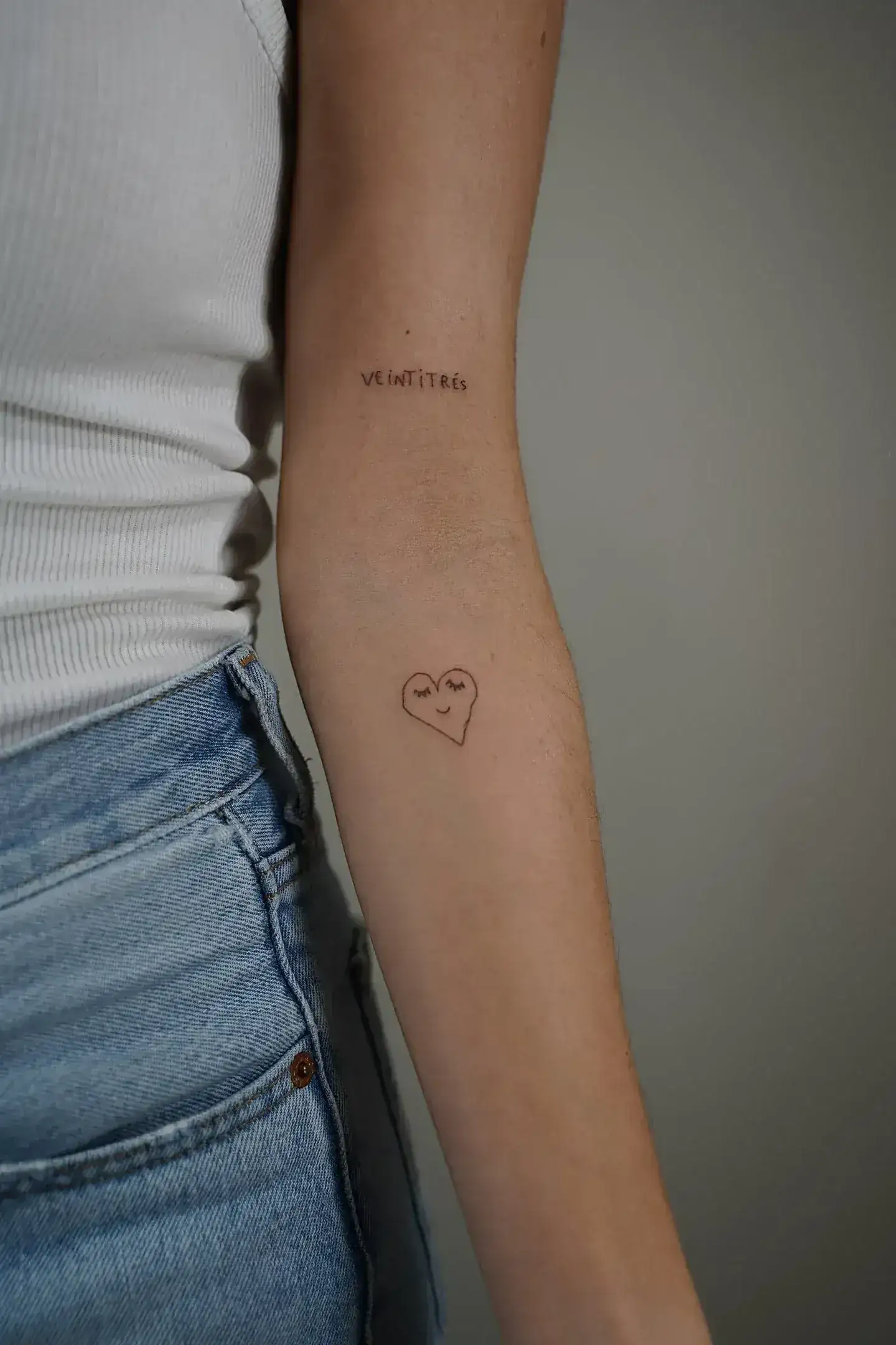 Fine line tattoo Madrid — abstract personal calligraphic stroke in extremely fine line on the forearm