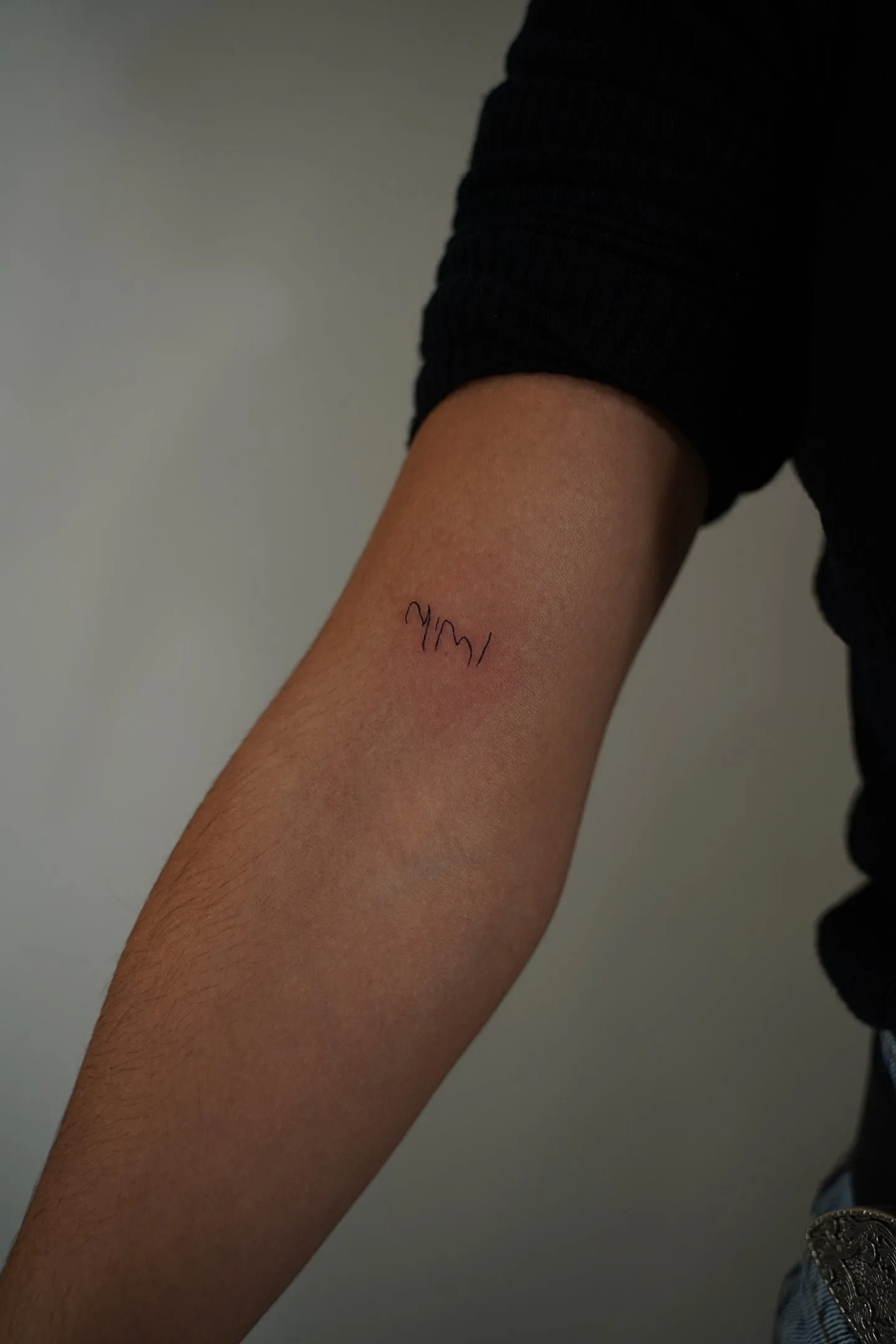 Fine line tattoo Madrid — mimi handwritten ultra-thin lettering on the forearm