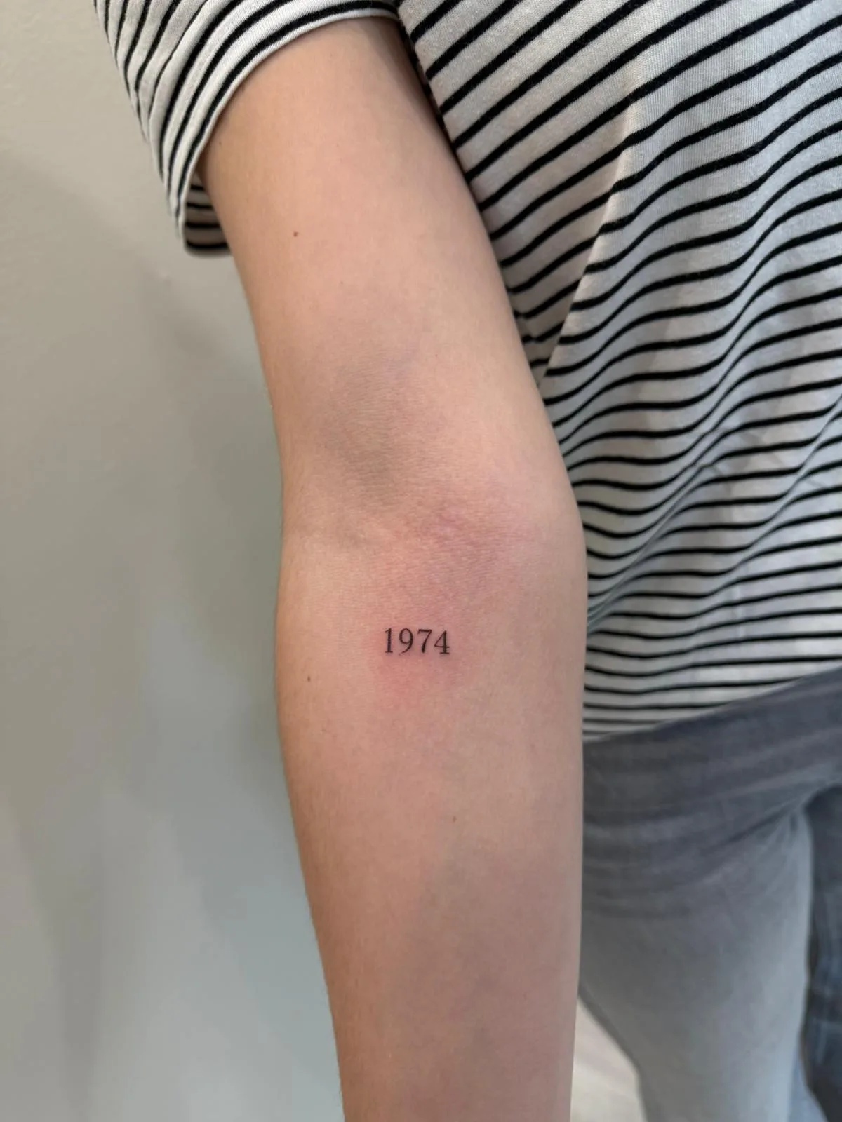 Frase motivacional corta con tipografía serif extrafina en el brazo